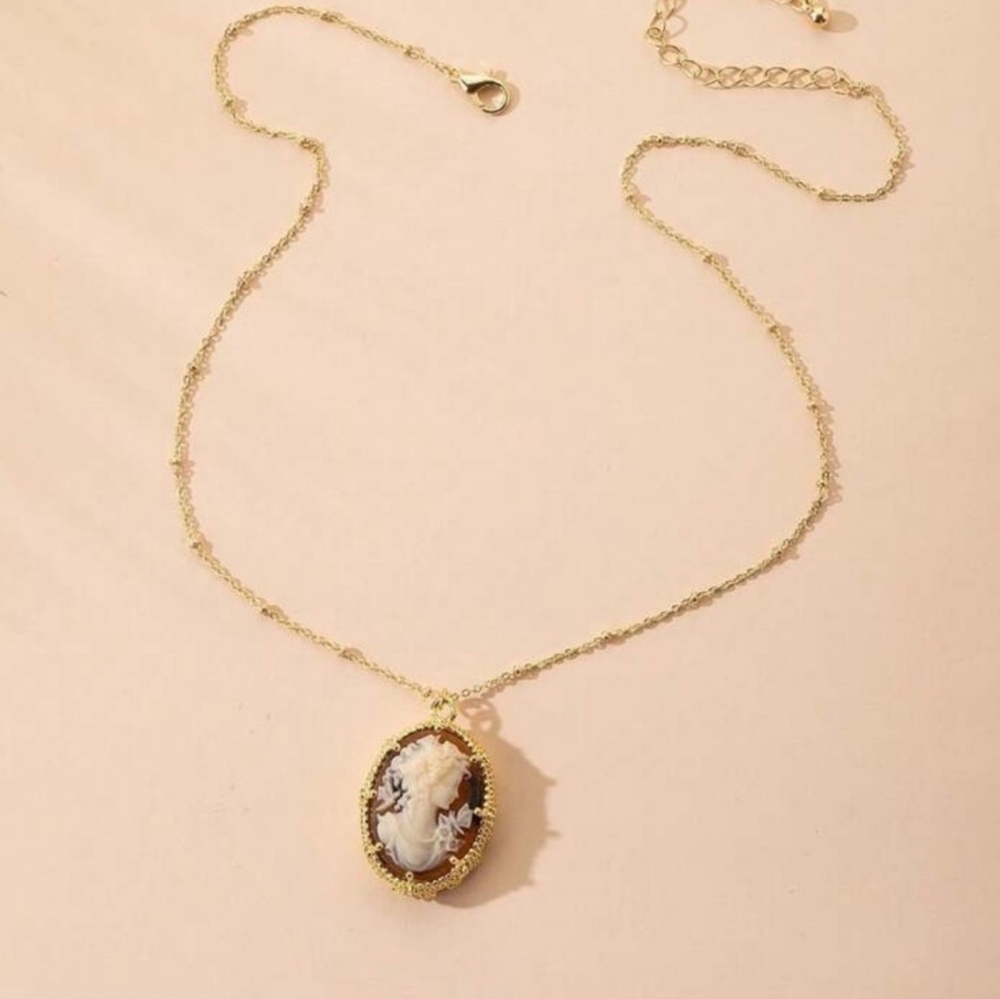 Gold cameo broach with amber brown background